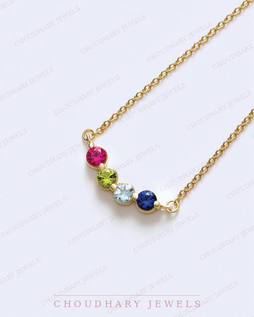 A yellow gold necklace with four round gemstones in a gentle curve: pink, green, light blue and dark blue.