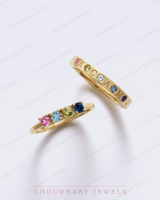 Two yellow gold rings: one set with a row of five round colored gemstones, and one engraved band with colored stones set between the letters.