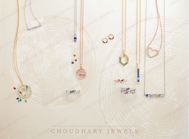Many family pendants, rings and earrings with colored gemstones, including a family tree pendant, a heart, a hexagon and bar necklaces, on a cream background.
