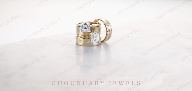 A yellow gold solitaire engagement ring with a matching band and a wide yellow gold band, on a white surface.