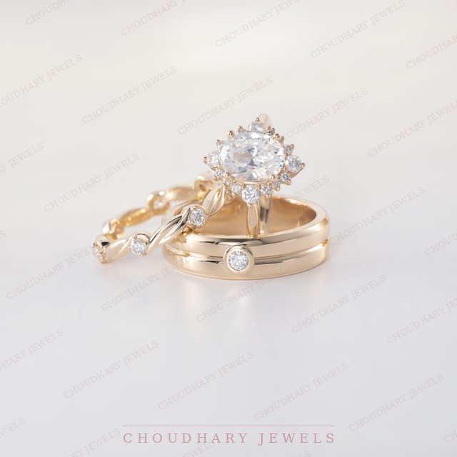 A yellow gold oval diamond engagement ring with a curved diamond accent, beside a twisted rose gold band and a yellow gold band with a bezel-set diamond.