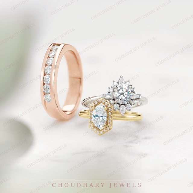 A rose gold channel-set diamond band beside a white gold ring with a round diamond and a yellow gold hexagon halo ring with an oval diamond.