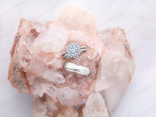 A white gold round halo engagement ring with a split band and a plain white metal band, on a pink quartz crystal.