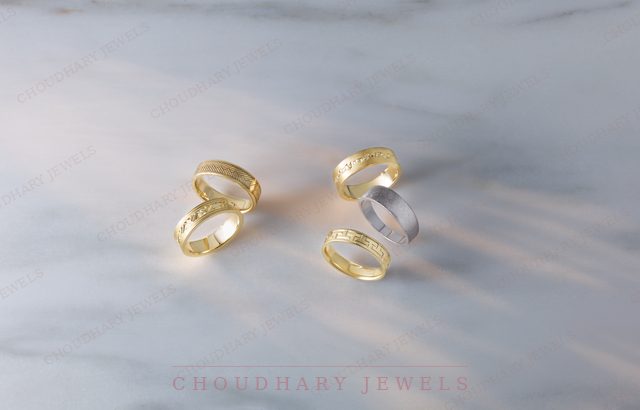 Several yellow gold and white gold patterned wedding bands on blue and white marble.