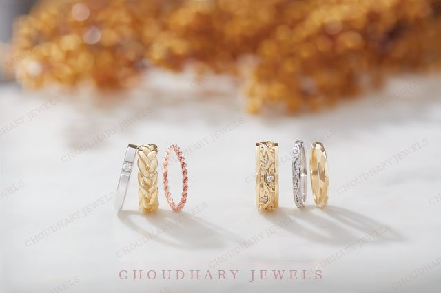 Two sets of stacked bands in white, yellow and rose gold with engraved and stone-set designs, on a white surface.